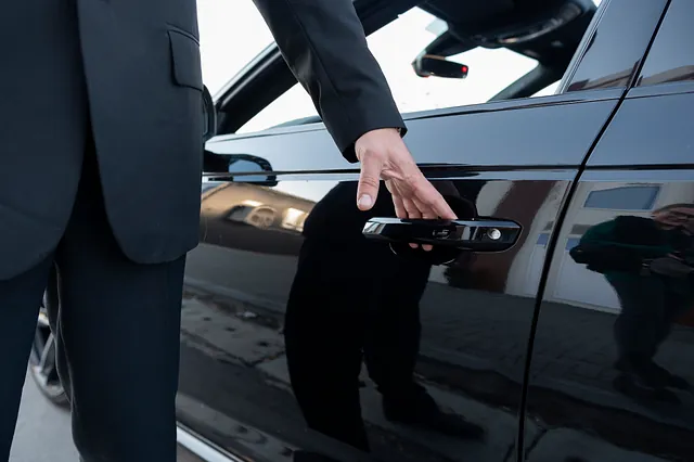 taxichaufför som ska öppna dörren på en svart bil